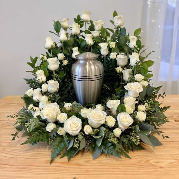 White rose wreath around a silver urn on a table