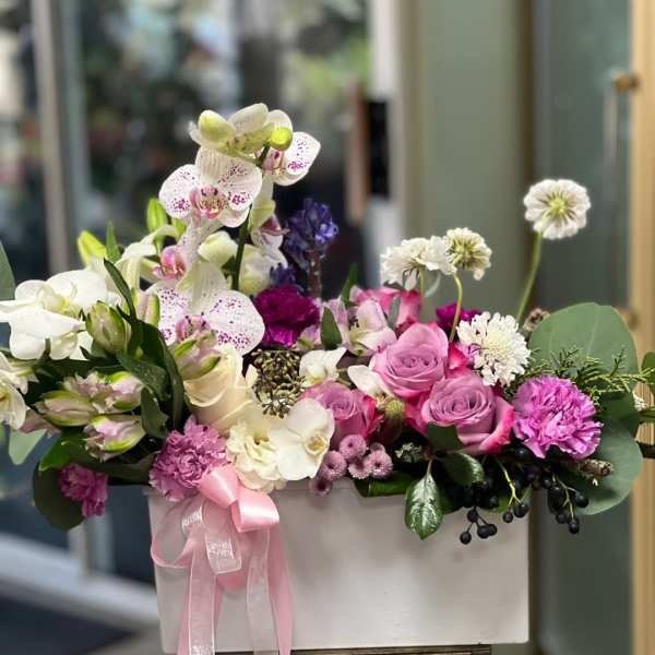Pink and white floral arrangement in a white box with a ribbon