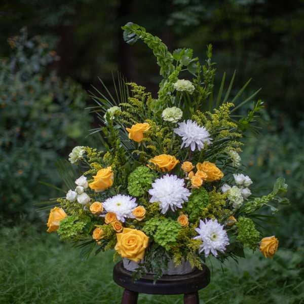 Yellow and white floral arrangement in a vase with greenery