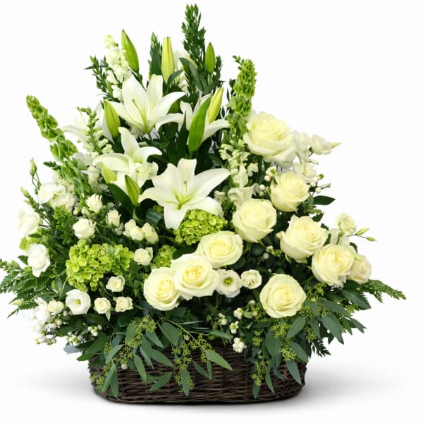 White lilies and roses arranged in a wicker basket