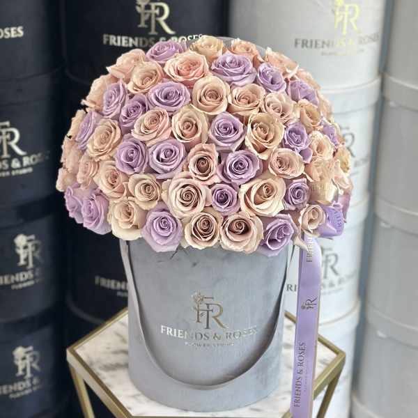 Bouquet of pastel pink and lavender roses in a gray hatbox