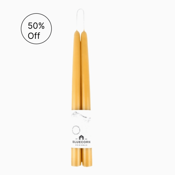 Pair of golden taper candles wrapped together with a white Bluecorn Beeswax label