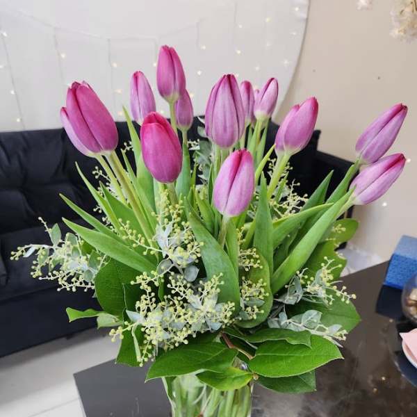 Bouquet of pink and purple tulips arranged in a clear glass vase on a table