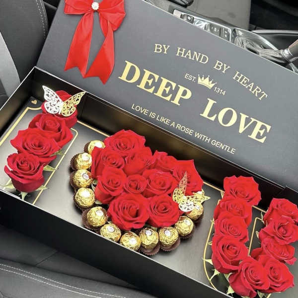 Red roses and chocolates arranged in a black gift box
