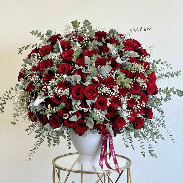 Large bouquet of red roses with baby's breath in a white vase