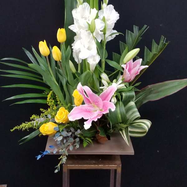 Tall floral arrangement with pink lilies, white gladiolus, and yellow tulips