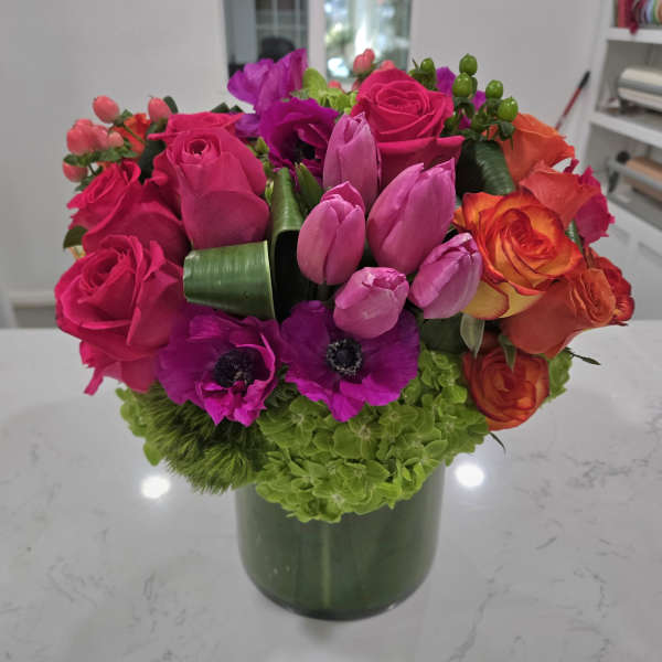 Bright mixed bouquet in a green vase with pink, purple, and orange flowers