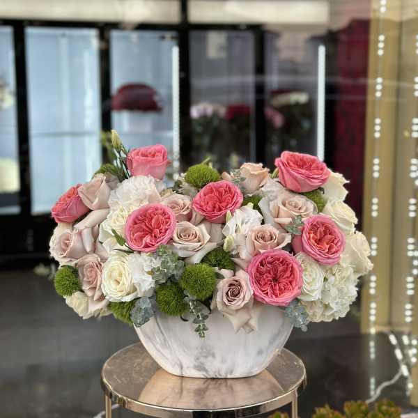 Pink and white roses arranged in a white vase