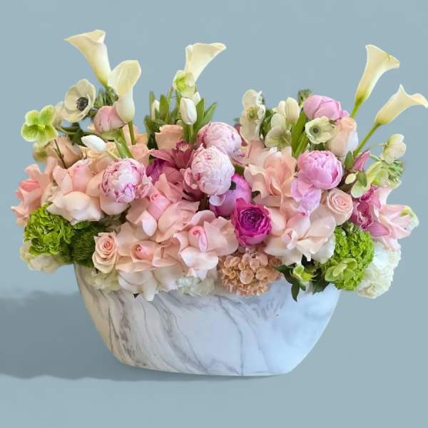Pastel floral arrangement in a marble-patterned vase with calla lilies and roses