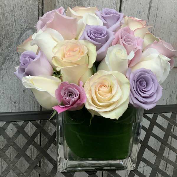Pastel roses arranged in a clear square vase