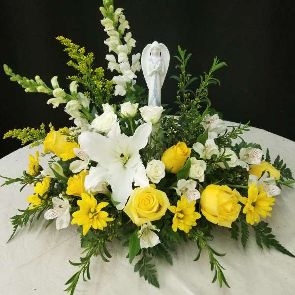 Yellow and white floral arrangement with a small angel figurine