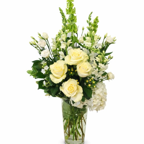 Cream roses and white flowers arranged in a clear glass vase