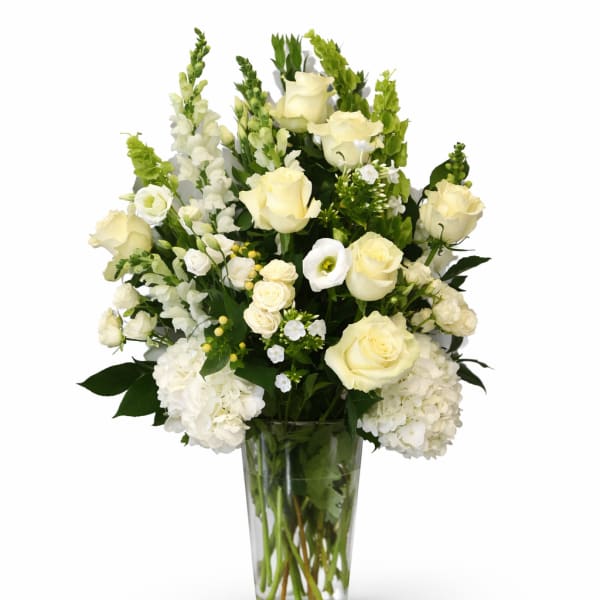 White roses and hydrangeas arranged in a clear glass vase