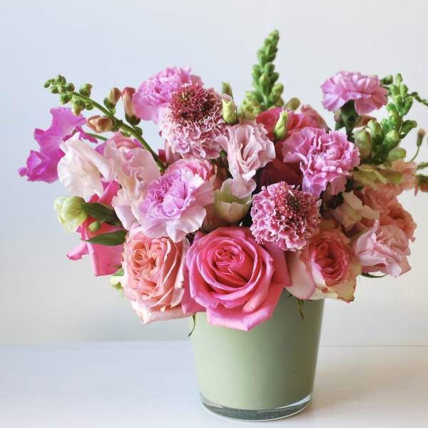 Pink and peach bouquet of roses and carnations in a green vase