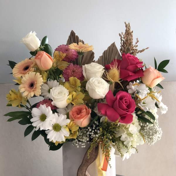 Mixed bouquet of roses, daisies, and gerbera daisies in a tall box