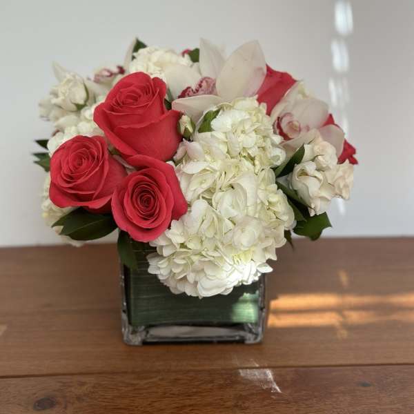 Red roses and white hydrangeas in a square glass vase
