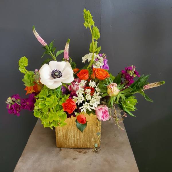 Colorful mixed flower arrangement in a gold square vase