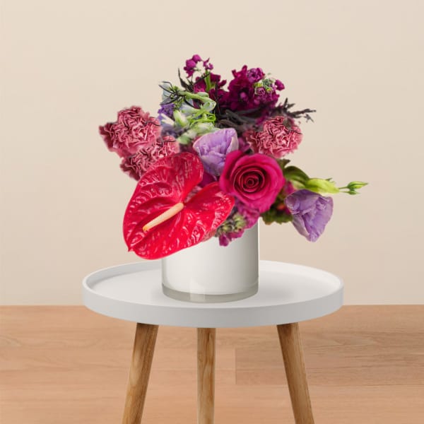 Bright pink and purple bouquet in a white vase