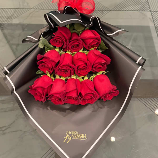 Bouquet of red roses wrapped in black paper with a red ribbon