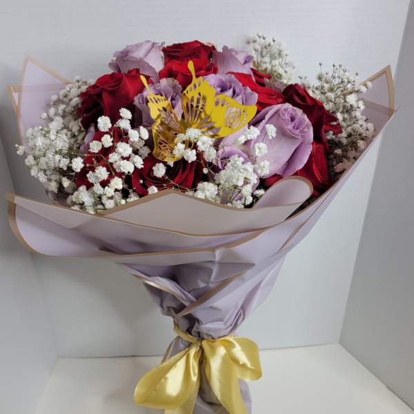 Bouquet of red and lavender roses with white baby's breath and a yellow butterfly topper