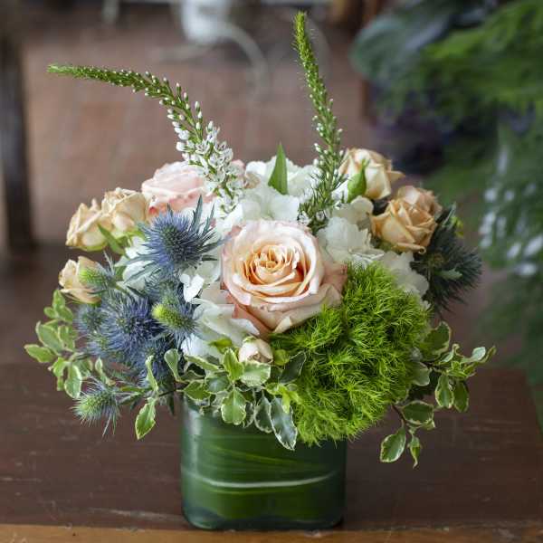 Bouquet of peach and white roses in a green glass vase