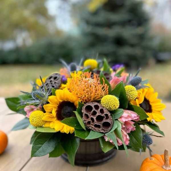 Autumn bouquet with sunflowers and orange blooms in a low container