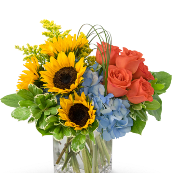Bouquet of sunflowers, blue hydrangeas, and coral roses in a glass vase