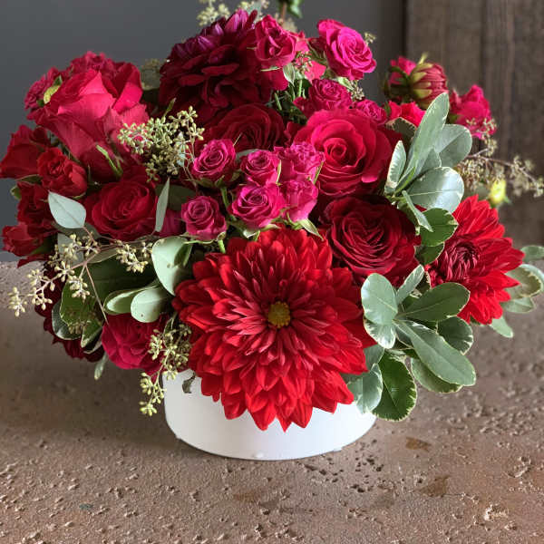 Red and pink flower arrangement in a white vase