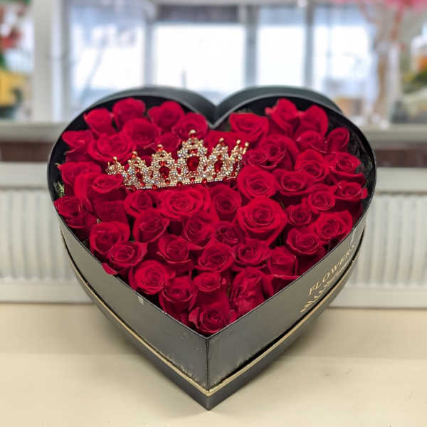 Heart-shaped black box filled with red roses and a jeweled crown ornament on top