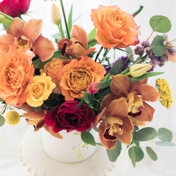 Bouquet of orange and red flowers in a white vase
