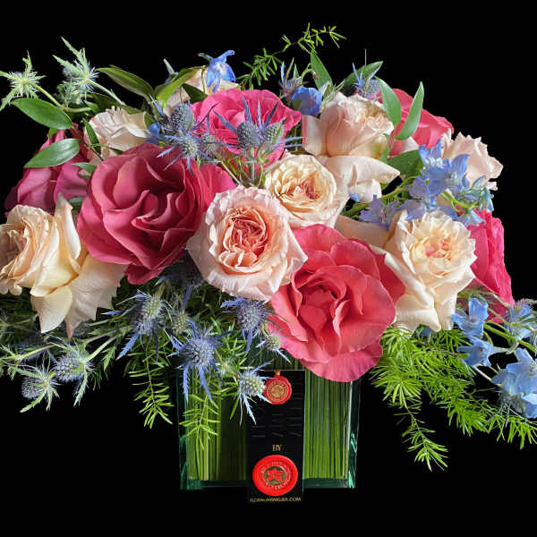 Bouquet of pink and cream roses with blue flowers in a glass vase