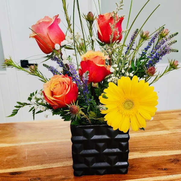Mixed bouquet with roses and a yellow gerbera daisy in a black vase