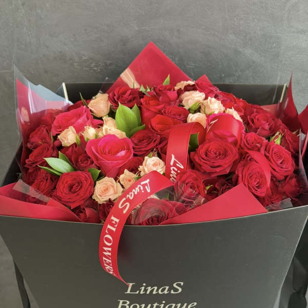 Bouquet of red and blush roses in a black gift box with a red ribbon