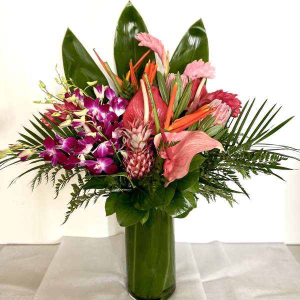 Tropical bouquet with pink orchids and anthurium in a green glass vase