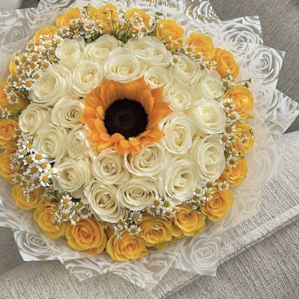 Round bouquet of white and yellow roses with a sunflower center