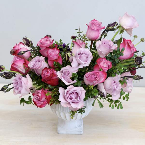 Low pink and lavender rose arrangement in a white pedestal bowl