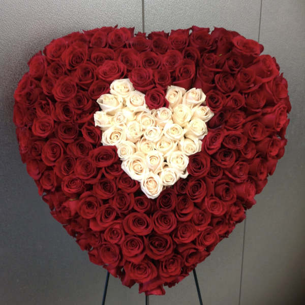 Heart-shaped arrangement of red and white roses on a stand