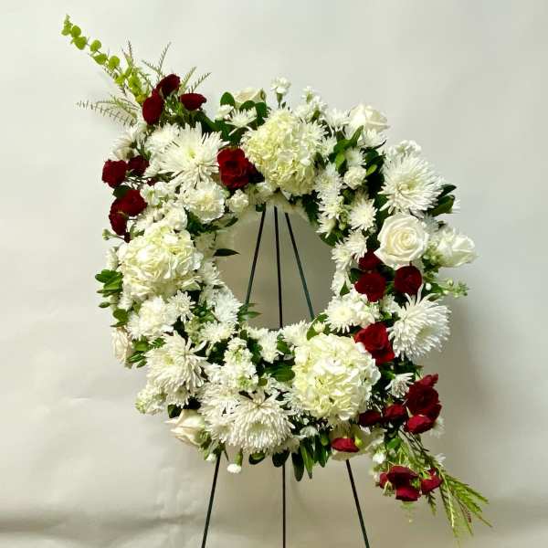 White and red floral wreath on a black stand