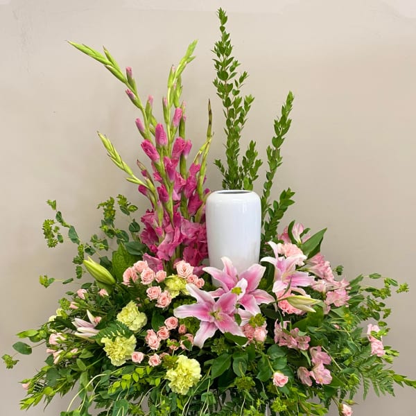 Large floral arrangement with pink lilies, roses, and tall greenery in a white vase