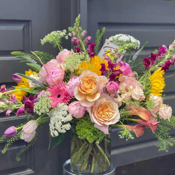 Mixed bouquet of pink, peach, and yellow flowers in a glass vase