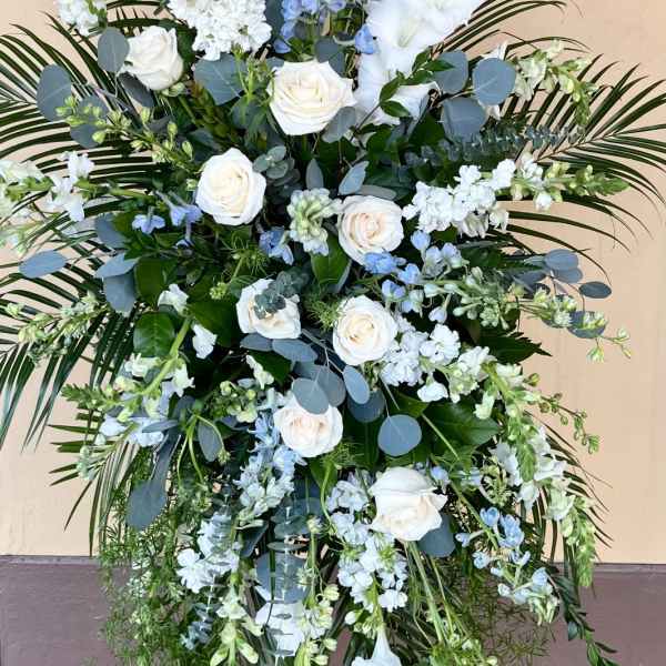 Tall white and blue floral standing spray on an easel