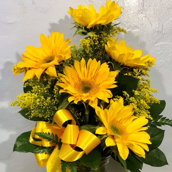 Yellow sunflower arrangement in a glass vase with a yellow ribbon
