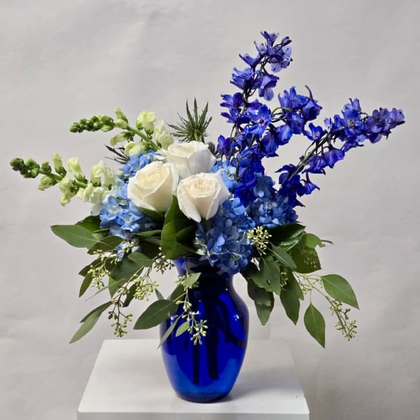 White roses and blue flowers in a cobalt vase