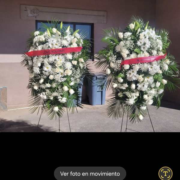 Two large white floral standing sprays on easels with pink ribbons