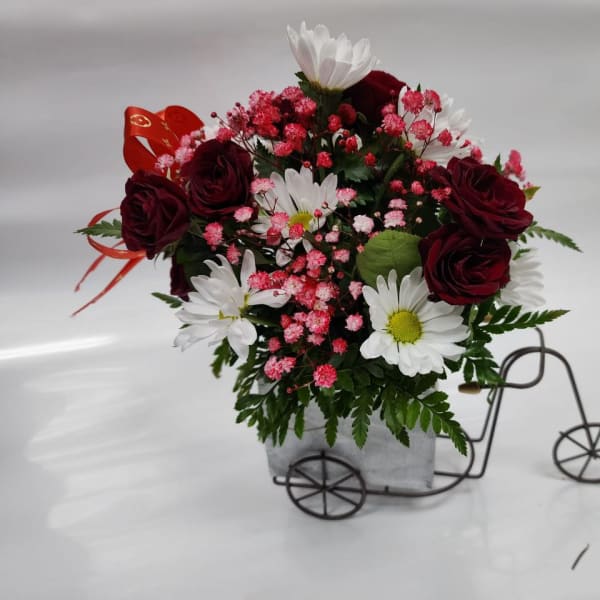 Bouquet of red roses and white daisies in a small bicycle planter