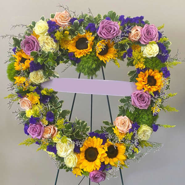 Heart-shaped floral wreath with sunflowers and roses on an easel