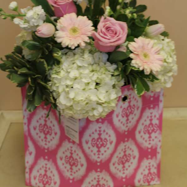Pink roses and pale gerbera daisies in a patterned gift bag