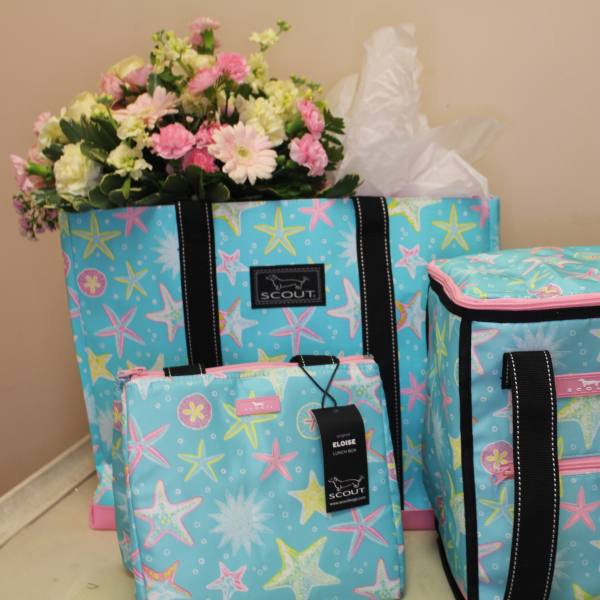 Pink and white flowers arranged in a blue patterned tote with matching bags
