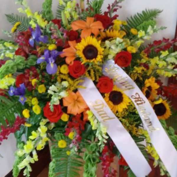 Large standing floral spray with sunflowers, roses, and ribbons