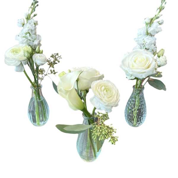 Three white floral arrangements in blue glass vases